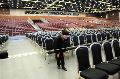 昨日，国家会议中心大会堂，一名服务员在以线为参照物摆齐凳子，屋顶的灯全换成LED灯。新京报记者 秦斌 摄