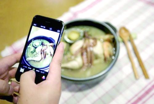 一名韩国男子用手机拍摄自己亲手做的参鸡汤。